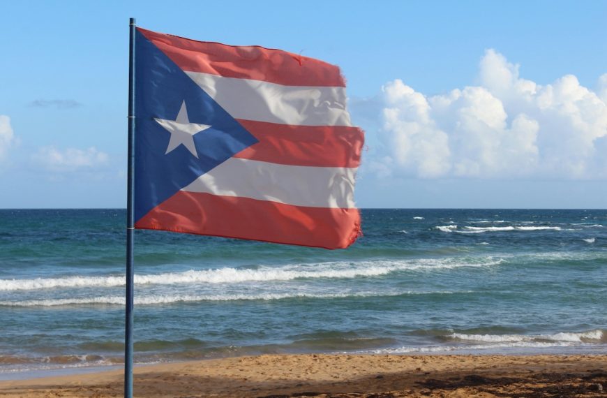 Photo of a Ripped Puerto Rican Flag on a Flagpole on a beach.