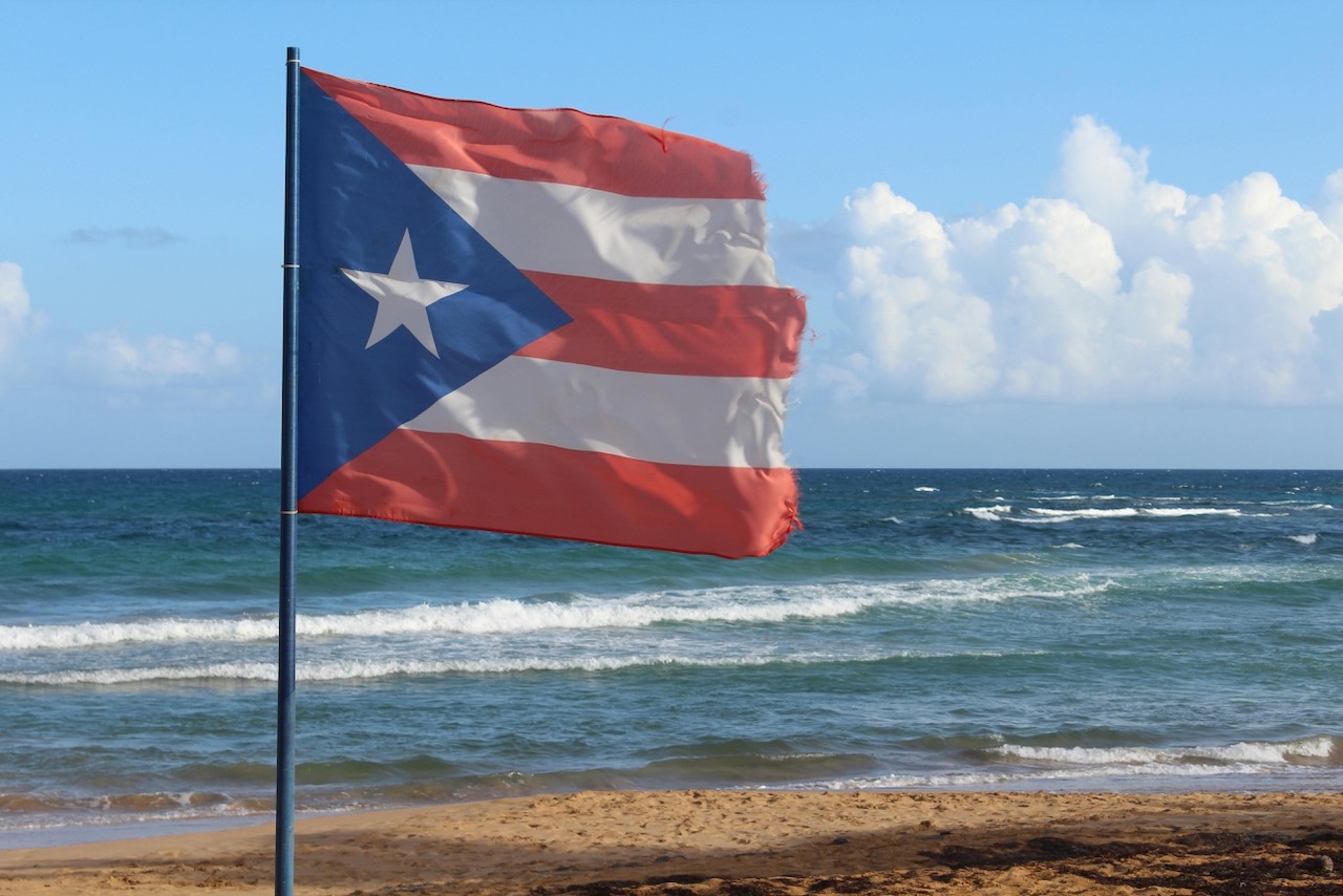 Photo of a Ripped Puerto Rican Flag on a Flagpole on a beach.