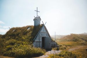 Photo of an Aged wooden church on grassy meadow in sunlight in Newfoundland, Canada.