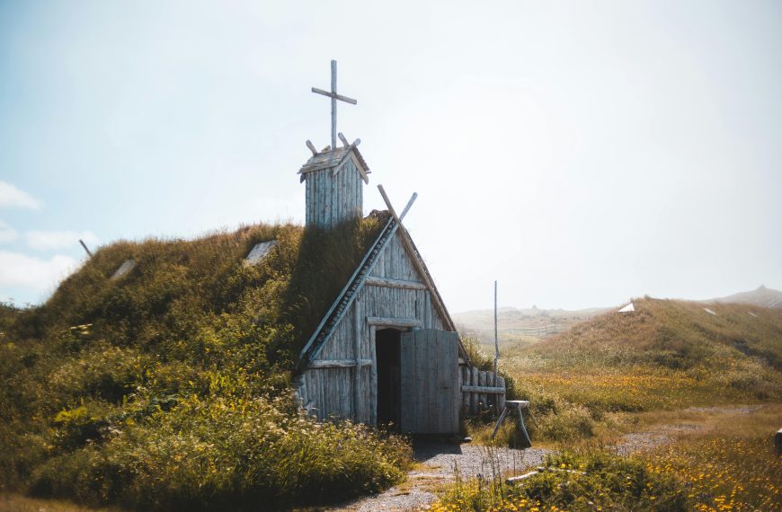 Photo of an Aged wooden church on grassy meadow in sunlight in Newfoundland, Canada.