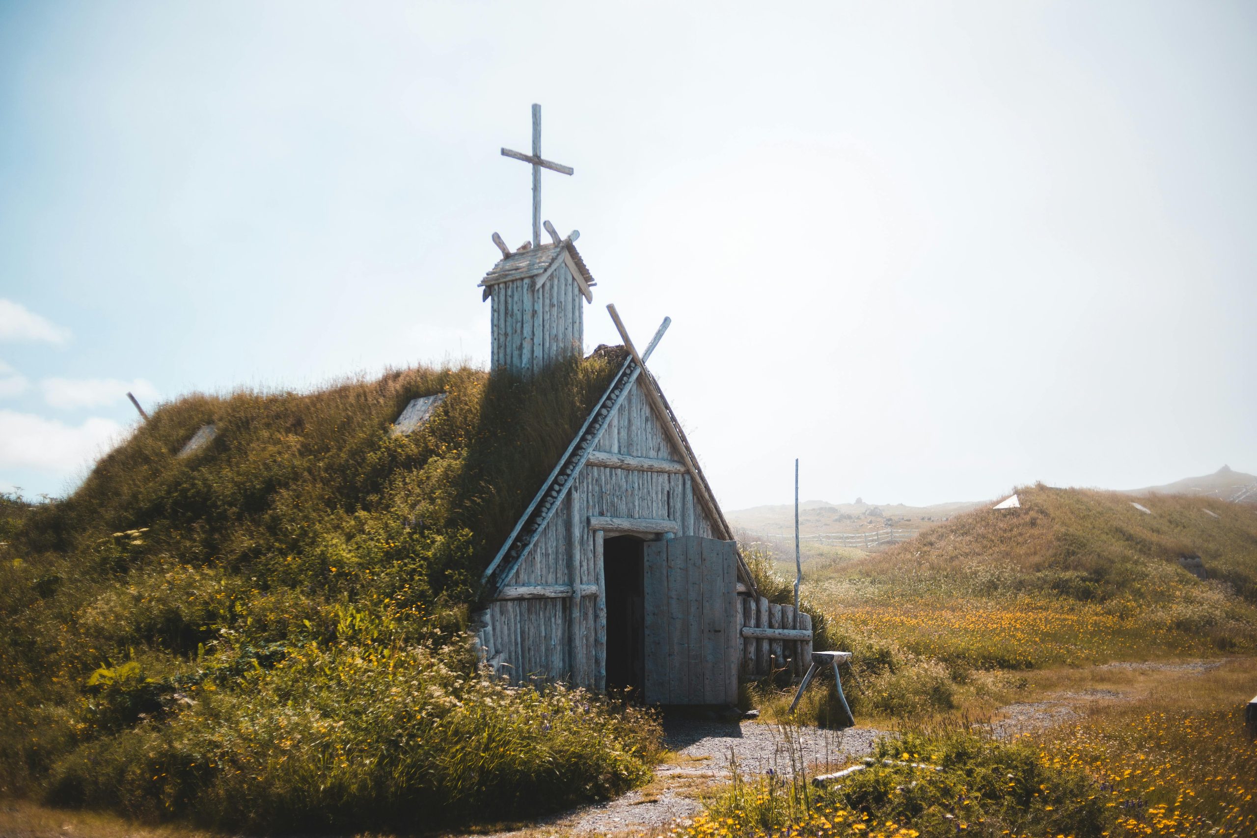 Photo of an Aged wooden church on grassy meadow in sunlight in Newfoundland, Canada.