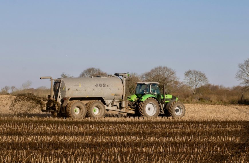 A Tractor Fertilizing Brown Field