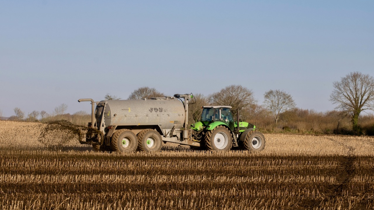 A Tractor Fertilizing Brown Field