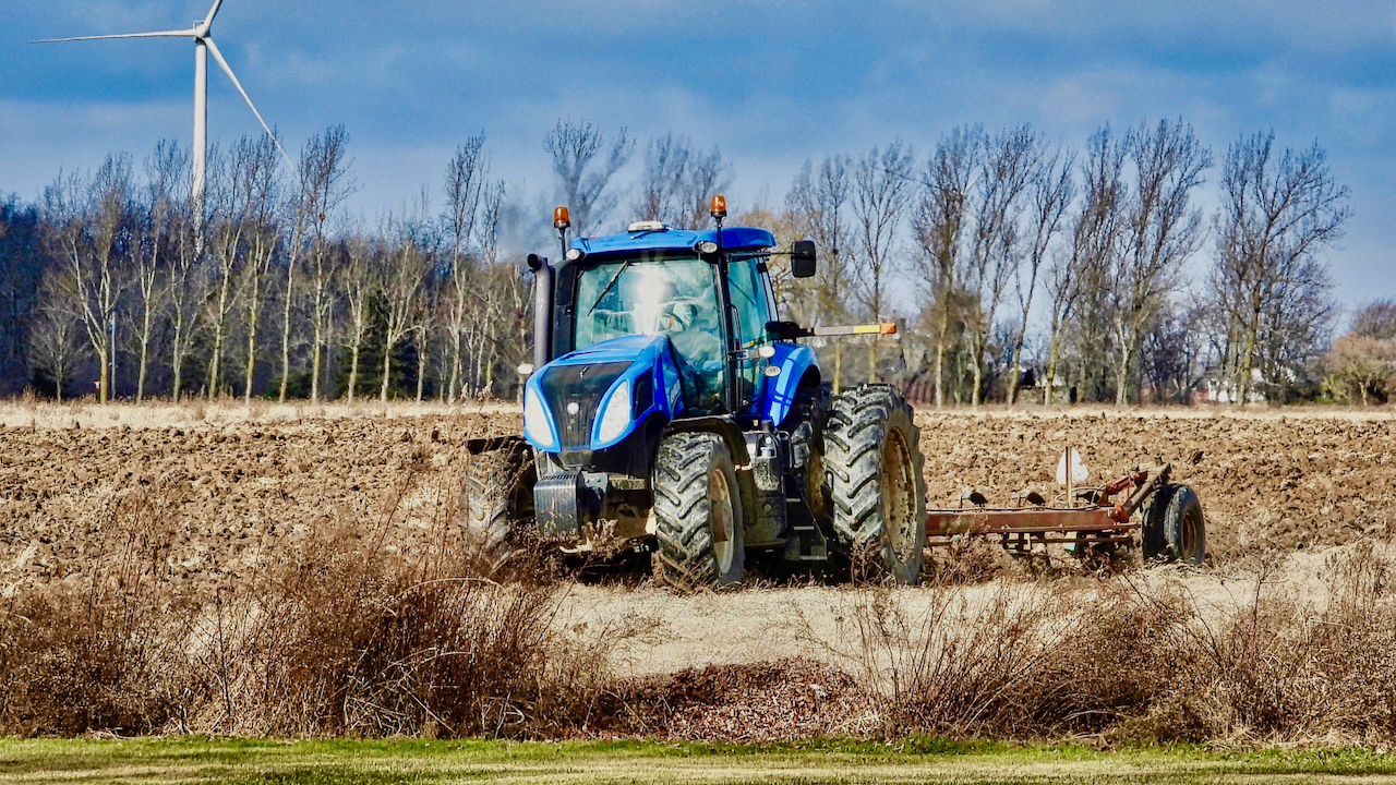 Photo of a blue tractor plowing a field in Ontario, Canada.
